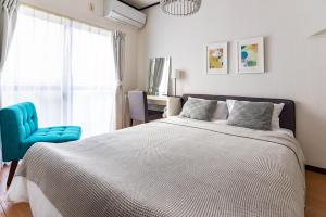 a bedroom with a large bed and a blue chair at Tino Anastasia in Osaka