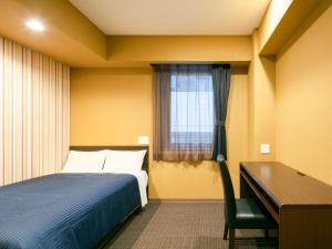 a bedroom with a bed and a desk and a window at HOTEL LiVEMAX Sendai Aobadori in Sendai