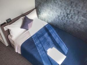 Schlafzimmer mit einem Bett mit blauer und weißer Bettwäsche in der Unterkunft HOTEL LiVEMAX Okayama in Okayama