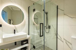 a bathroom with a shower and a sink and a mirror at Airedale Boutique Suites in Auckland