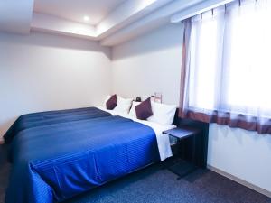 a bedroom with a blue bed with a window at HOTEL LiVEMAX Shinsaibashi East in Osaka