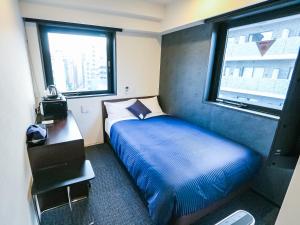 HOTEL LiVEMAX Tokyo Shintomicho في طوكيو: غرفة نوم صغيرة بها سرير ونافذة