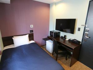 a hotel room with a bed and a desk with a television at HOTEL LiVEMAX Asakusabashi-Eki Kitaguchi in Tokyo