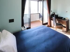 a bedroom with a blue bed with a desk and a window at HOTEL LiVEMAX Asakusabashi-Eki Kitaguchi in Tokyo