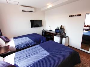 a hotel room with two beds and a desk at HOTEL LiVEMAX Osaka Dome Mae Hotel in Osaka
