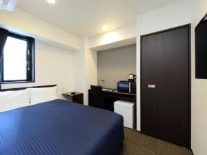 Habitación de hotel con cama azul y escritorio. en HOTEL LiVEMAX Meieki, en Nagoya