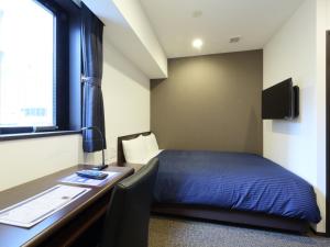 1 dormitorio con 1 cama y escritorio con ordenador en HOTEL LiVEMAX Meieki, en Nagoya