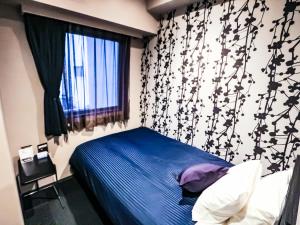 a bedroom with a blue bed and a window at HOTEL LiVEMAX Tokyo-Otsuka Ekimae in Tokyo