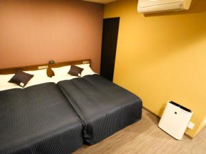 une chambre d'hôtel avec un lit et une couverture noire dans l'établissement HOTEL LiVEMAX Mikawaanjo Ekimae, à Anjomachi