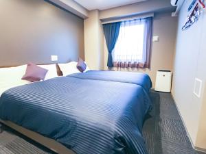 um quarto com uma cama grande e uma janela em HOTEL LiVEMAX Yokohama-Eki Nishiguchi em Yokohama