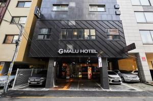 a hotel entrance with cars parked in a parking lot at Malu Hotel Suwon in Suwon