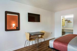 Habitación de hotel con cama, mesa y sillas en Motel 6-Warner Robins, GA, en Warner Robins