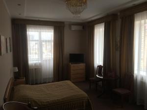 a bedroom with a bed and a television and windows at Altyn Adam Hotel in Pavlodar