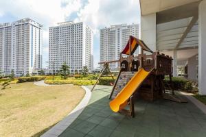 a playground with a slide in a yard with tall buildings at 2Bedroom Unit Wind Residences by SMCo in Tagaytay