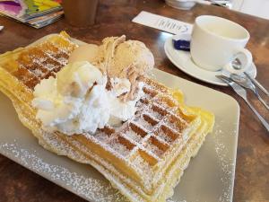 a plate of waffles with ice cream and a cup of coffee at Fewo Baltic Dreams in Börgerende-Rethwisch