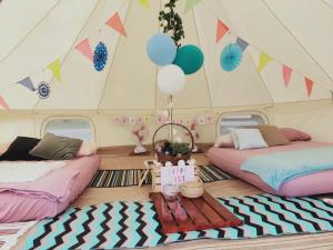 two beds in a tent with balloons and a table at Glamping Kaki - Medium Bell Tent in Singapore