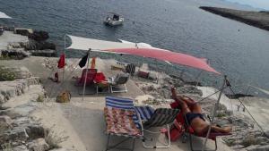 a person laying in chairs under an umbrella on the beach at Foissner Apartments in Zavalatica