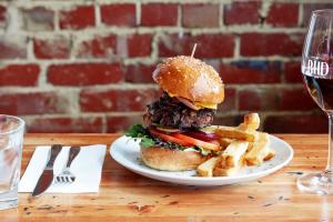 a hamburger and french fries on a plate with a glass of wine at The Royal Hotel, Drouin in Drouin