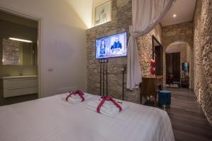 a bedroom with a bed with a tv on a stone wall at Suite via Sulis 61 in Cagliari