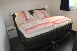 1 cama con almohadas y mantas rosas y blancas en 5*Ferienwohnung Seeblick 4, en Wendisch Rietz