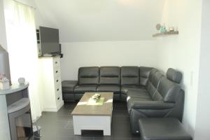 sala de estar con sofá de cuero negro y mesa en 5*Ferienwohnung Seeblick 4, en Wendisch Rietz