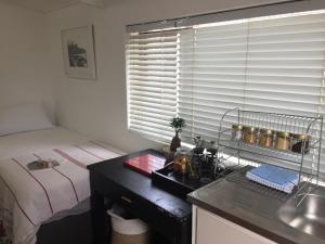 een slaapkamer met een bed, een bureau en een raam bij Just a Bed in Stellenbosch