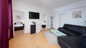 ein Wohnzimmer mit einem schwarzen Sofa und einem TV in der Unterkunft Boardinghouse - Stadtvilla Budget in Schweinfurt