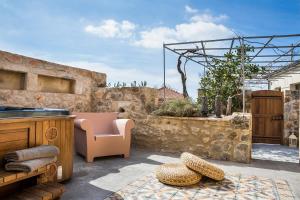 a patio with a stone wall and a chair and a table at Villa Daniela - Saint Nikolas Retreat in Faraklata