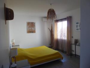 una camera con letto giallo e finestra di Gîte des Jonquiès, au calme vue sur le canal du midi et la mer a Portiragnes