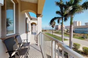a balcony with two chairs and palm trees at Campeche Retreat #2 in South Padre Island