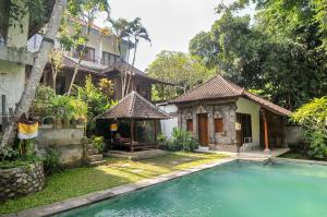 a house with a swimming pool in front of a house at Yuliati House in Ubud