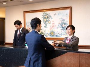 Un uomo e una donna che stringono la mano a una scrivania di Ark Hotel Kumamotojo Mae -ROUTE INN HOTELS- a Kumamoto