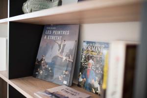 Zwei Bücher sitzen auf einem Bücherregal in der Unterkunft Le Tout à Pied et son parking privé in Étretat