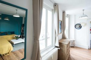 ein Schlafzimmer mit einem Spiegel, einem Bett und einem Fenster in der Unterkunft Le Tout à Pied et son parking privé in Étretat