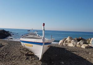 a boat sitting on a beach near the ocean at El Nogal Home in Málaga
