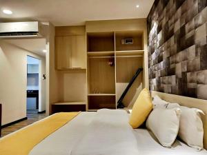 een slaapkamer met een groot wit bed en een bakstenen muur bij Kidurong Inn in Bintulu