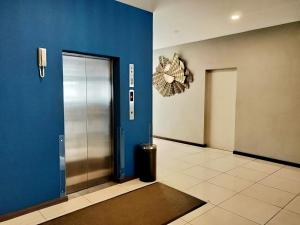 a hallway with a metal elevator and a blue wall at Kidurong Inn in Bintulu