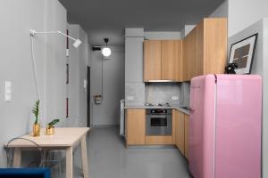 ブダペストにあるLucifer Apartmentのピンクの冷蔵庫とテーブル付きのキッチンが備わります。