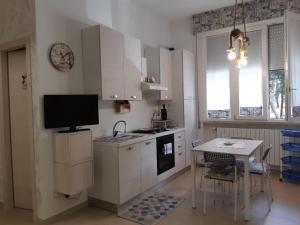 una cucina con armadi bianchi, tavolo e TV di casa vacanza sissi a Viareggio
