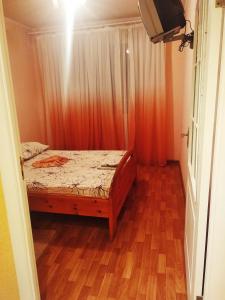 a small bedroom with a bed and a wooden floor at Tiraspol Apartments in Tiraspol