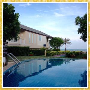 a swimming pool in front of a house at ห้องชุด 2 ห้องนอน ริมหาด ณ บ้านทะเลสำราญ ชะอำ in Ban Khlong Khot