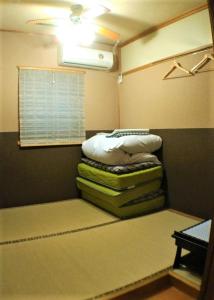Habitación con 3 pilas de almohadas y ventana en Dyeing and Hostel Nakashimaya - Female Only, en Kumamoto
