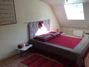 1 dormitorio con 1 cama con edredón rojo y ventana en le grenier d'Annick, en Villefort