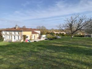 um grande quintal com uma casa e uma árvore em Les Marmottes Charentaises em Tonnay-Boutonne