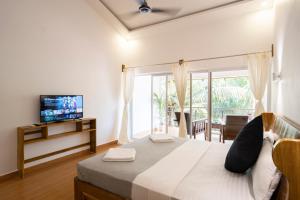 Schlafzimmer mit einem Bett, einem TV und einem Fenster in der Unterkunft Crystall Goa Emerald Edition in Patnem