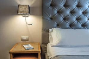 a bed with a lamp and a table with a book at Hotel Elite in Rome
