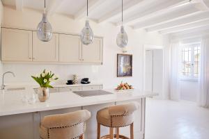 a kitchen with white cabinets and a counter with stools at Old Town Luxury Suites 'Princess' in Corfu