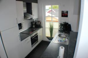 uma cozinha com armários brancos, um lavatório e uma janela em 5*Ferienwohnung Seeblick 4 em Wendisch Rietz
