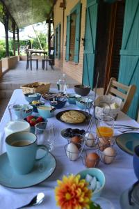 a table with cups and plates of food on it at Les Terrasses des Mimosas in Caumont-sur-Garonne