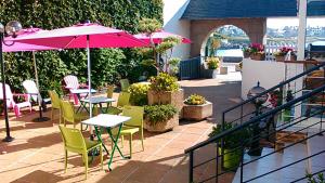 un patio avec des tables, des chaises et des parasols dans l'établissement Logis Hotel Bellevue, à Roscoff